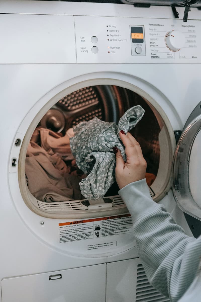 Main déposant du linge dans une machine à laver